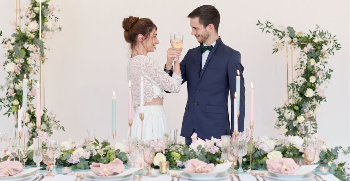 couple de mariés qui trinque avec un mariage rose bleu pastel et blanc