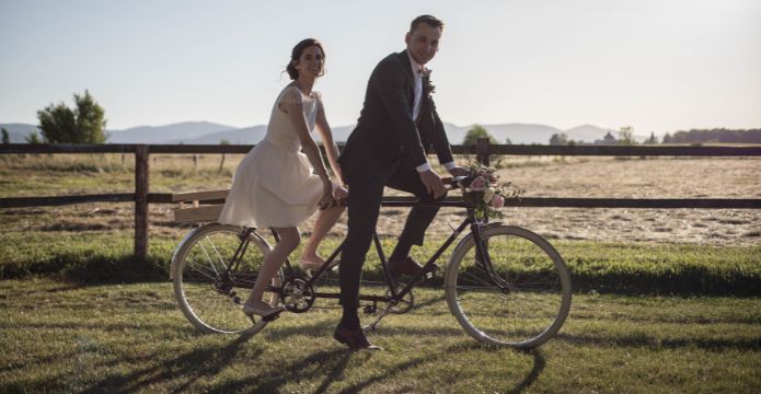 photo de mariés en vélo dans les champs pour un mariage champêtre
